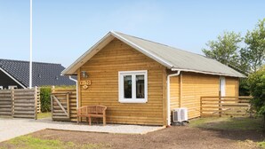 Une petite cabane en bois avec un toit en pente, un banc à l’extérieur et une pancarte portant le numéro 112.