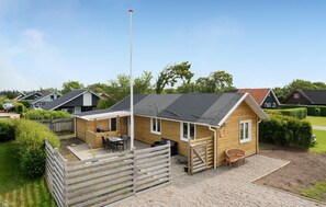 A wooden cabin with a patio, a flagpole, and a view of neighboring houses. - 2 bedroom beautiful home in Hemmet (Hemmet)