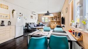 Une cuisine moderne avec des meubles blancs, un coin repas doté de chaises turquoise et une table à manger en bois.