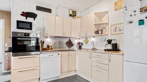 Une cuisine moderne avec des meubles blancs, des appareils en acier inoxydable et un micro-ondes noir.