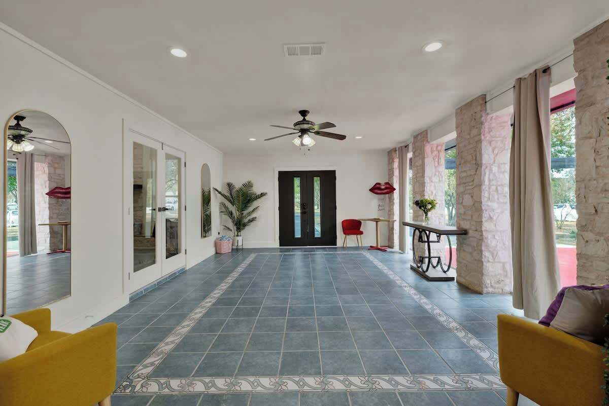 A spacious hallway with a tiled floor, a ceiling fan, and a door leading to another room.