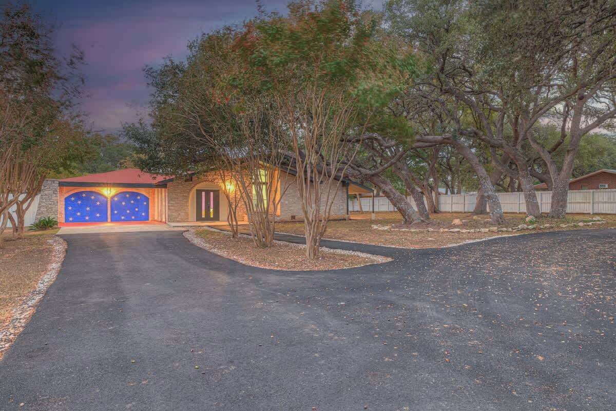 A house with a driveway leading to a garage with two blue doors.