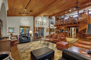 A spacious living area with leather furniture, wooden beams, and a staircase leading to an upper level. - The Willows Casa Grande + Sundown Suite Sleeps 13 - Close to Main St (Fredericksburg)