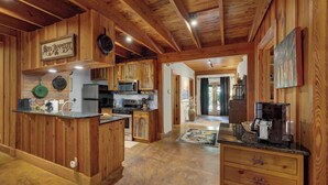 A spacious kitchen with wooden cabinets, a central island, and a dining area with a rug. - The Willows Casa Grande + Sundown Suite Sleeps 13 - Close to Main St (Fredericksburg)