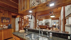 A kitchen with granite countertops, stainless steel sink, wooden cabinets, and a wooden ceiling. - The Willows Casa Grande + Sundown Suite Sleeps 13 - Close to Main St (Fredericksburg)