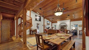 A spacious dining area with a wooden table set for six, a wooden staircase, and a chandelier. - The Willows Casa Grande + Sundown Suite Sleeps 13 - Close to Main St (Fredericksburg)