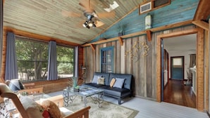 A spacious living area with a wooden ceiling, a sofa, a coffee table, and a view of the outdoors.