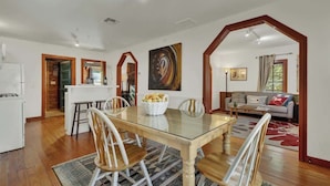 A dining area with a glass-top table, wooden chairs, and a basket of bread.