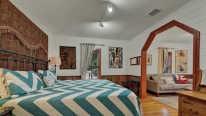 A bedroom with a large bed, a sofa, and a wooden archway.