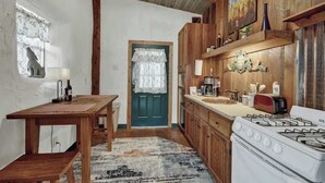 A rustic kitchen with wooden cabinets, a stove, a sink, and a dining table. - Sonora Casita Hot-tub Four Minutes to Marktplatz! (Fredericksburg)