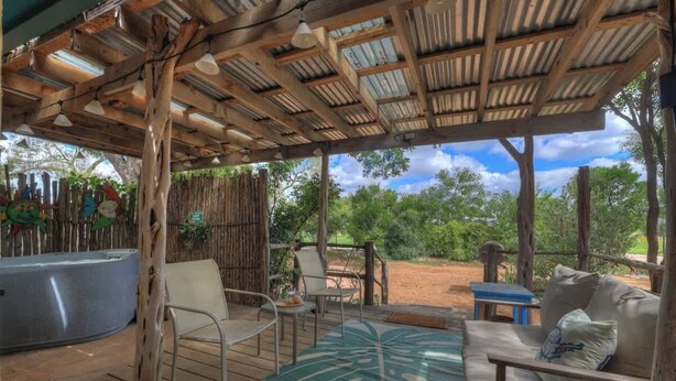 An outdoor patio with wooden furniture, a hot tub, and a view of the surrounding greenery. - Sonora Casita Hot-tub Four Minutes to Marktplatz! (Fredericksburg)