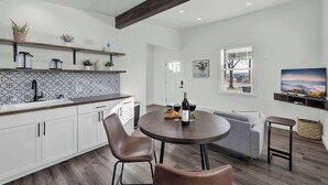A modern kitchen with white cabinets, a patterned backsplash, and a wooden ceiling beam. - Evergreen Escape W/hot-tub 5 Min to Downtown! (Fredericksburg)