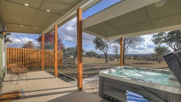 A covered outdoor area with a hot tub, wooden deck, and chairs. - Evergreen Escape W/hot-tub 5 Min to Downtown! (Fredericksburg)