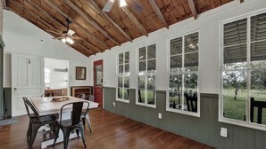 A spacious dining area with a wooden ceiling, large windows, and a view of the outdoors. - Rocking Ox Gasthaus and Barn Cabin (Fredericksburg)
