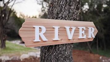 A wooden sign with the word "RIVER" mounted on a tree.