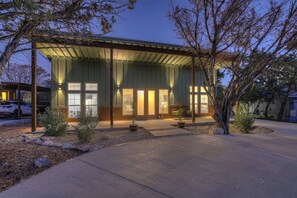 A modern house with a covered porch, large windows, and a well-maintained garden. - Serene Guadalupe River Getaway-river Access! (Spring Branch)
