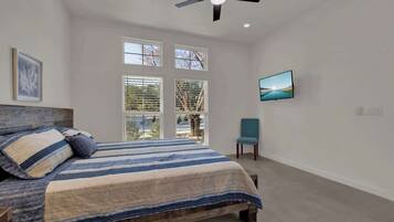 Un dormitorio con una cama, ventilador de techo, ventana y una silla.