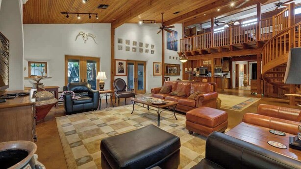 A spacious living area with leather furniture, wooden beams, and a staircase leading to an upper level.