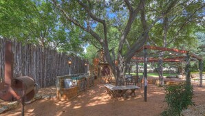 An outdoor patio with a grill, wooden tables, and a pergola.