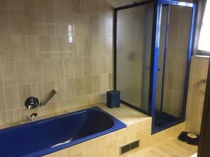 A bathroom with a blue bathtub, a shower enclosure, and a scale on the floor. - Holiday Home in Groede Near Sandy Beach (Groede)