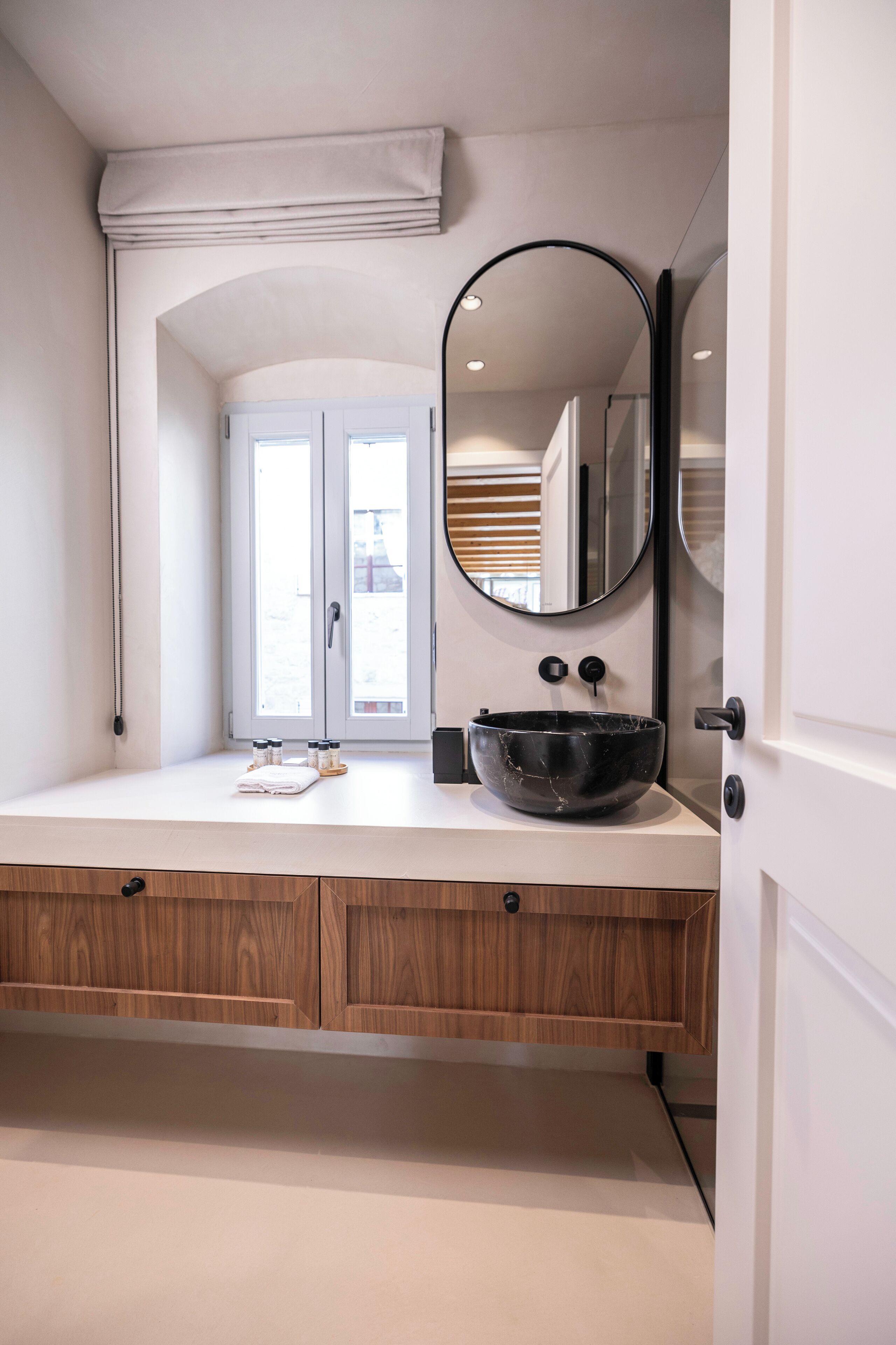 Une salle de bain moderne avec un grand miroir, un lavabo en marbre noir et des meubles en bois.