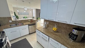 Eine moderne Küche mit weißen Schränken, Granit Arbeitsplatten, einer Kaffeemaschine und einem Geschirrspüler.