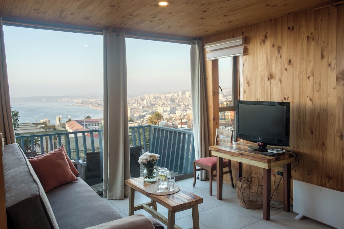 A balcony with a wooden desk, a TV, and a sofa.