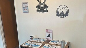 A room with a wooden table displaying 'Lakeside Dune Getaway' and 'Live to Ride' posters, a 'No Parking' sign, and a bench.