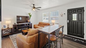 A living room with a sofa, a coffee table, a TV, and a dining table with chairs. - All American Cottage (Wichita Falls)
