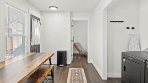 A modern kitchen with a wooden table, a trash bin, and a bench. - All American Cottage (Wichita Falls)