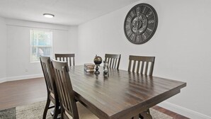 A dining area with a wooden table, four chairs, a wall clock, and a globe. - All American Lone Star (Wichita Falls)