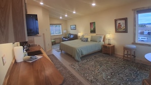 A bedroom with a bed, bedside tables, a desk, and a window. - GLACIER SUITE, BEACH WALK INN, UPPER LEVEL UNIT
FEATURING HOMER'S FANTASTIC VIEW (Homer)