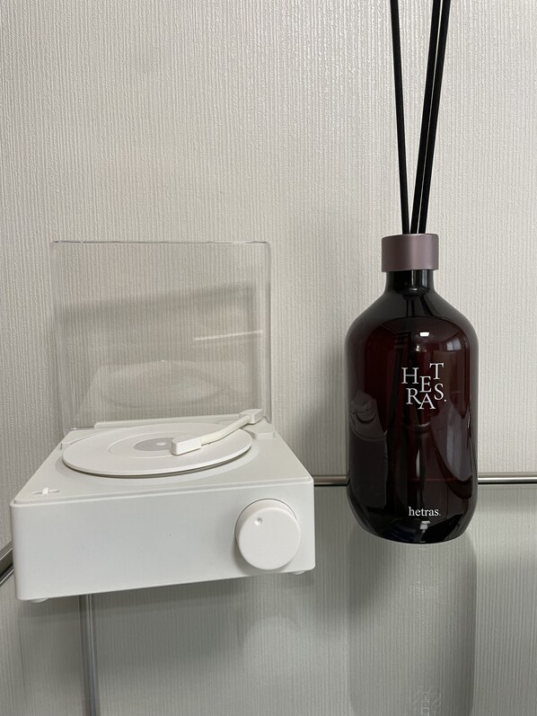 Un reproductor de música blanco con una cubierta plástica transparente y una botella oscura con pajitas negras y el texto 
