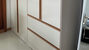Una habitación con puerta corredera y un armario blanco con detalles de madera.