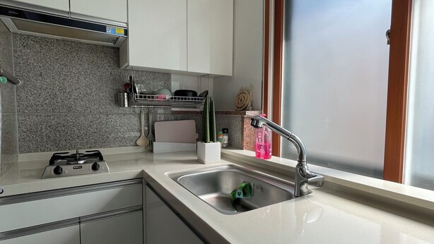 Una cocina moderna con armarios blancos, un lavamanos de acero inoxidable y una ventana con vistas.