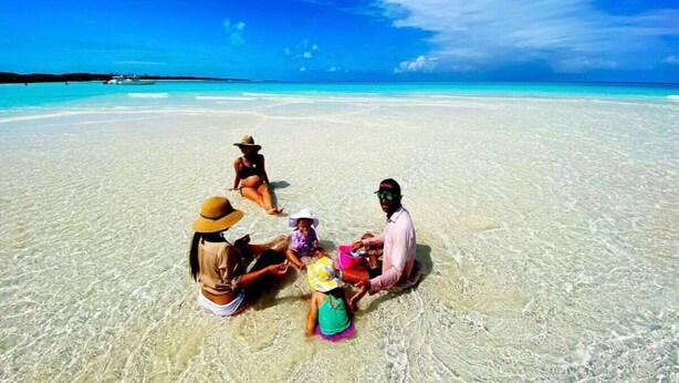 A group of people sitting on a beach with clear turquoise water and a blue sky. - Eleuthera Sailing Catamaran Adventure (Freetown)