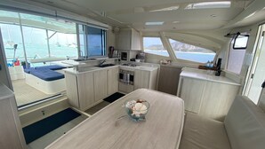 A compact galley with a central table, a stove, and a sink. - Eleuthera Sailing Catamaran Adventure (Freetown)