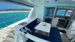 A yacht's deck with a seating area, a table, and a view of the ocean. - Eleuthera Sailing Catamaran Adventure (Freetown)