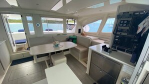 A compact kitchen area with a dining table, a small refrigerator, and a control panel. - Eleuthera Sailing Catamaran Adventure (Freetown)