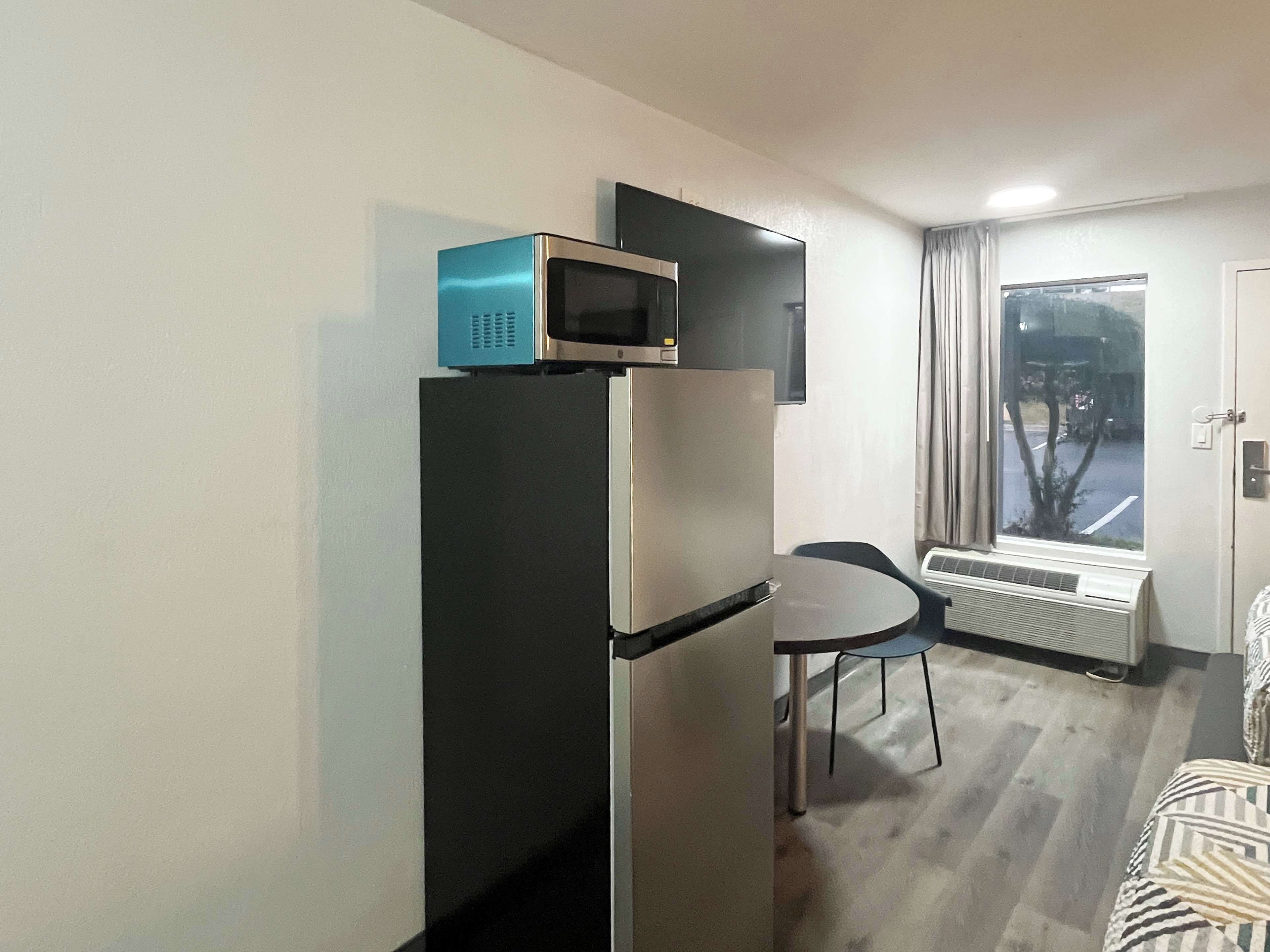 Une cuisine compacte équipée d’un réfrigérateur, d’un four à micro-ondes et d’une petite table à manger.