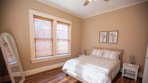 Une chambre à coucher avec un grand lit, une table de chevet, un miroir et deux tableaux accrochés au mur.