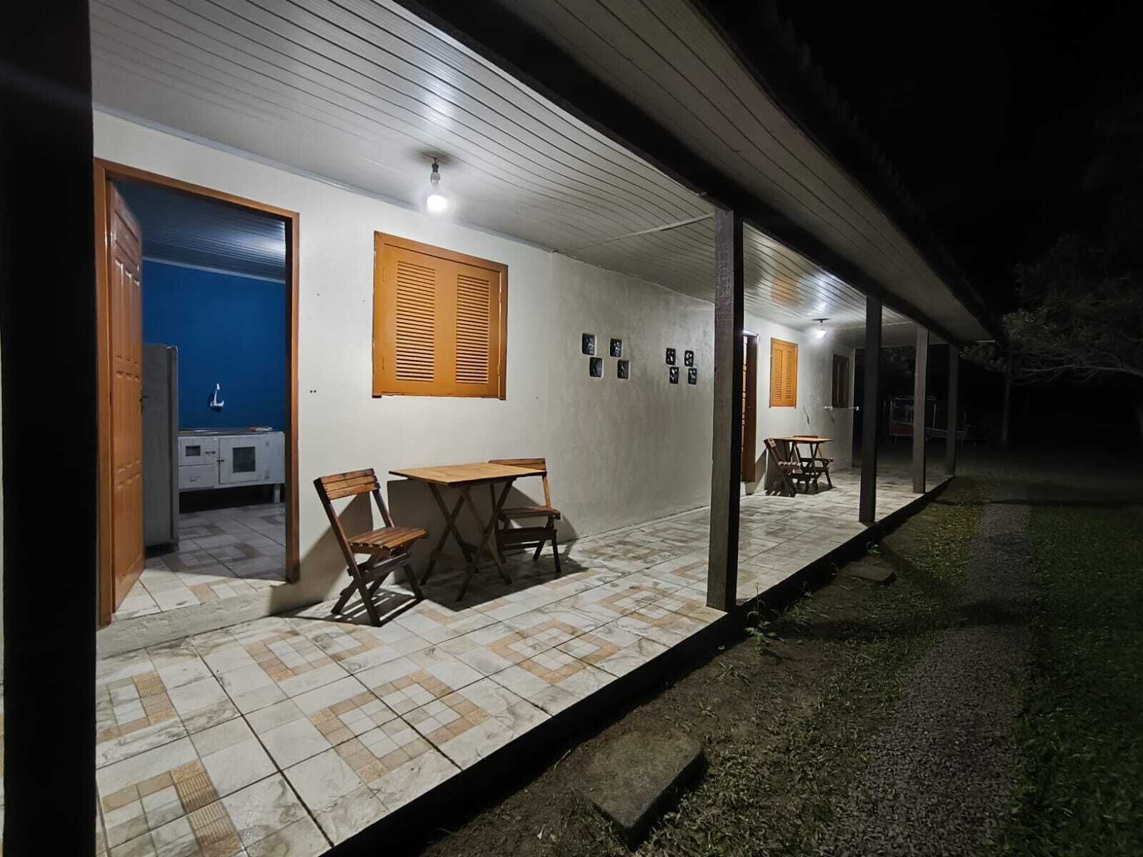 A covered outdoor patio with a table and chairs, a blue wall, and a door leading to a kitchen area.