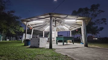 A covered outdoor area with a concrete floor, a green table, and a white structure.