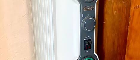 A white portable heater with a digital control panel, a power cord, and a safety lock.