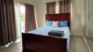 Una camera da letto con un letto in legno, una ventola a soffitto e un'ampia finestra con tende.