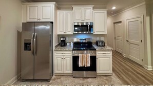 A modern kitchen with white cabinetry, stainless steel appliances, and granite countertops. - 1st fl, 3-bed condo, mins from beach, Marshwalk, and golf! (Murrells Inlet)
