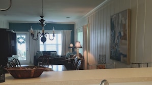 A kitchen with a white sink, a chandelier, and a dining area with a table and chairs.