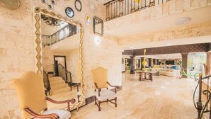 Eine geräumige Lobby mit hoher Decke, einer Treppe und einer Sitzecke mit zwei Sesseln.