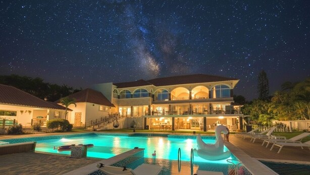 Ein großes, luxuriöses Haus mit Swimmingpool und einer Schwane als Schwimmfigur.