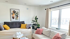 Un salon moderne avec un canapé, un lit, une table basse et une grande fenêtre.